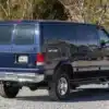 Dunkelblauer Ford E-350 Quigley 4x4 Campervan in einer Waldlandschaft