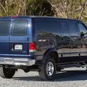 Dunkelblauer Ford E-350 Quigley 4x4 Campervan in einer Waldlandschaft