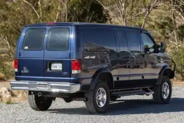 Dunkelblauer Ford E-350 Quigley 4x4 Campervan in einer Waldlandschaft