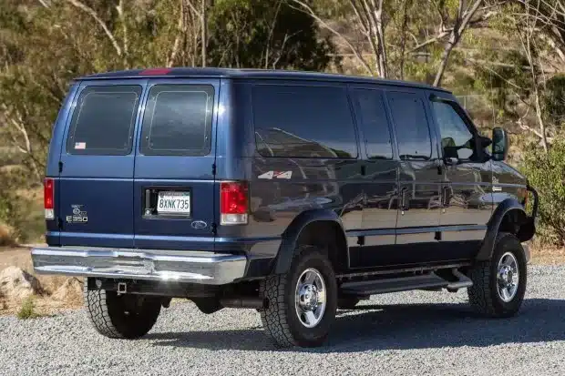 Dunkelblauer Ford E-350 Quigley 4x4 Campervan in einer Waldlandschaft
