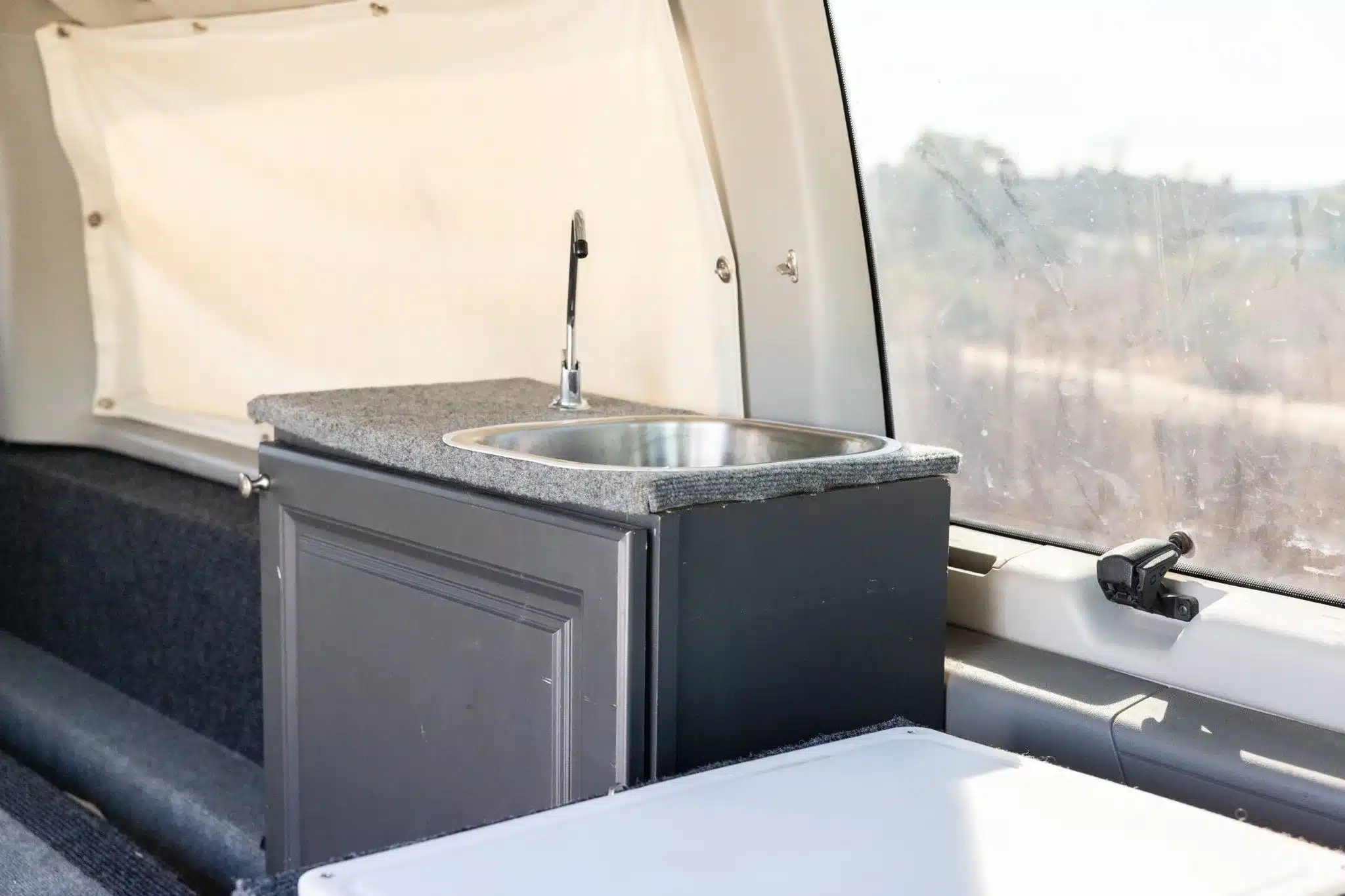 Innenraum des Ford E-350 Camperausbaus mit Spülbecken, Unterschrank und Schlafplattform