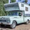 Mintgrüner Ford F-250 Pickup von 1961 mit großer weißer Wohnkabine auf einem Parkplatz