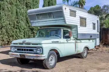 Mintgrüner Ford F-250 Pickup von 1961 mit großer weißer Wohnkabine auf einem Parkplatz