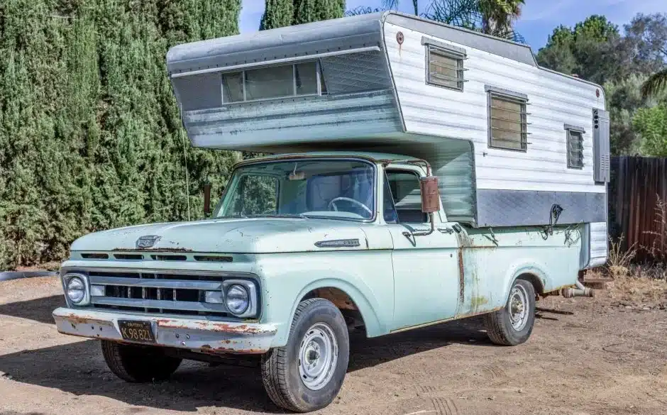 Mintgrüner Ford F-250 Pickup von 1961 mit großer weißer Wohnkabine auf einem Parkplatz