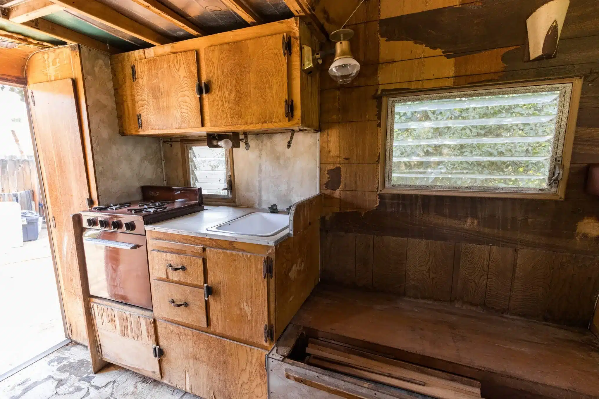 Innenraum der Wohnkabine eines Ford F-250 Custom Camper von 1961 mit Holzmöbeln, Dreiflammkocher, Spüle und Jalousiefenster