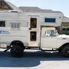 Weißer klassischer Ford F-350 Pickup mit silberner Wohnkabine vor einem Wohnhaus