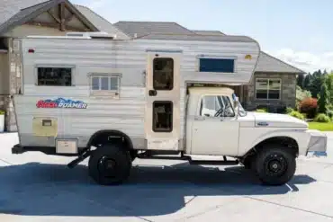 Weißer klassischer Ford F-350 Pickup mit silberner Wohnkabine vor einem Wohnhaus
