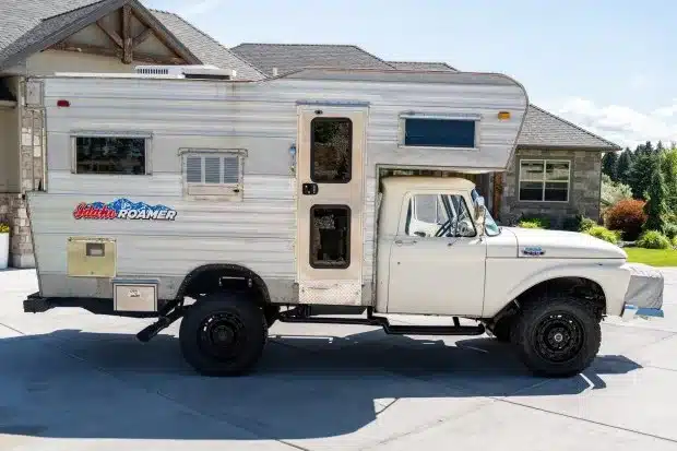 Weißer klassischer Ford F-350 Pickup mit silberner Wohnkabine vor einem Wohnhaus