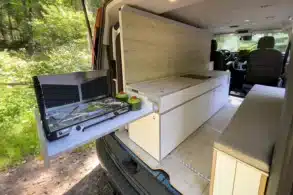 Innenraum eines Ford Transit Campervans mit Küchenmodul, Gaskocher, Stauraum und Sitzbank