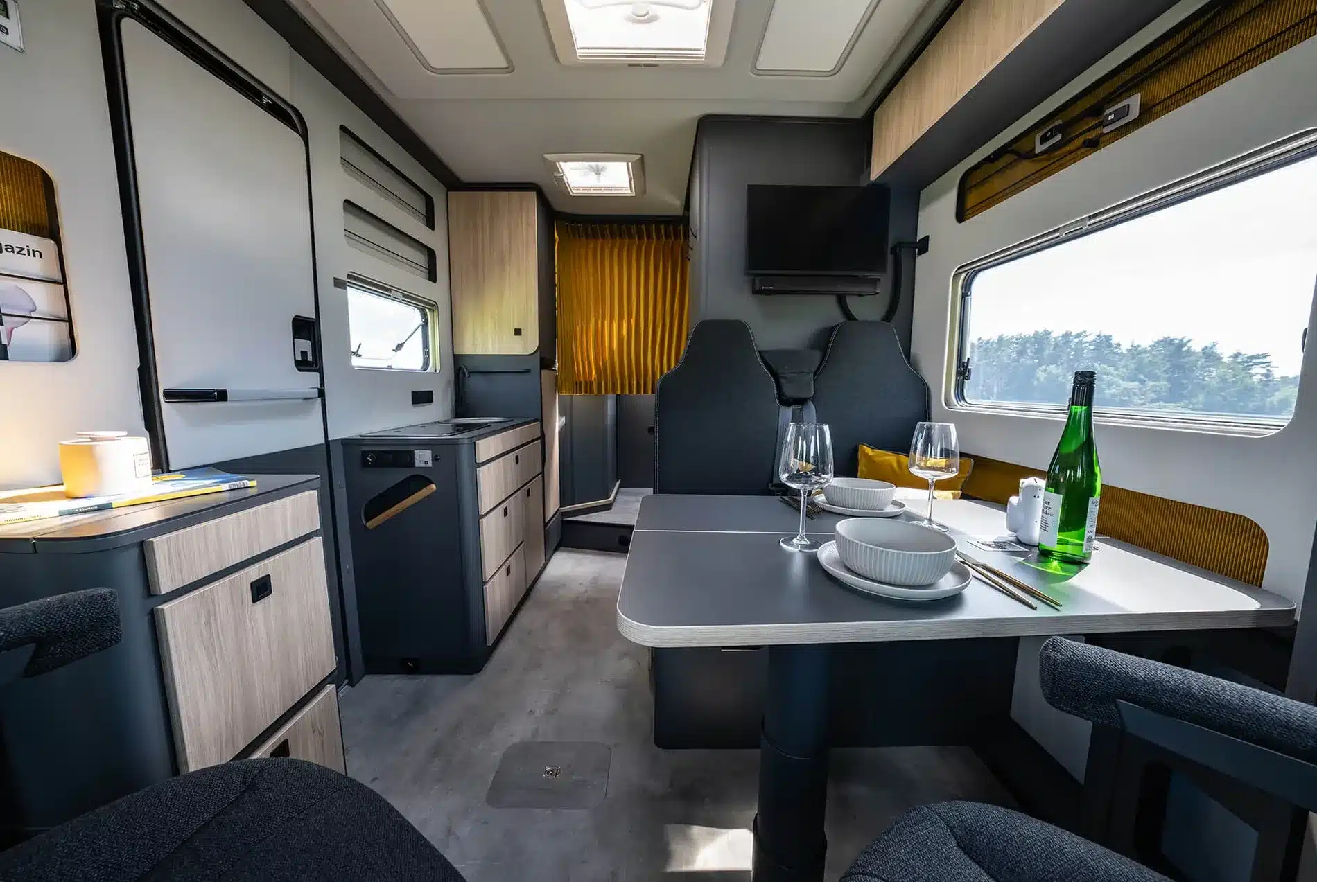 Innenraum des FRANKIA NOW 7.0 L mit Küche, Sitzgruppe, Esstisch, Fernseher und großen Fenstern