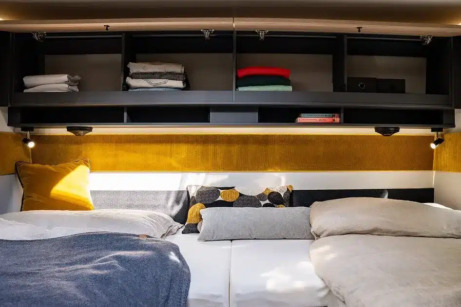 Schlafbereich des FRANKIA NOW 7.0 L mit Doppelbett, Oberschränken und Beleuchtung