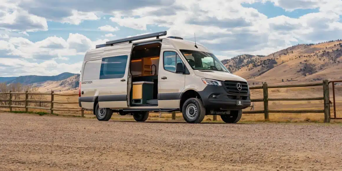 Weißer Geotrek Teton Campervan mit geöffneter Schiebetür vor einer Berglandschaft