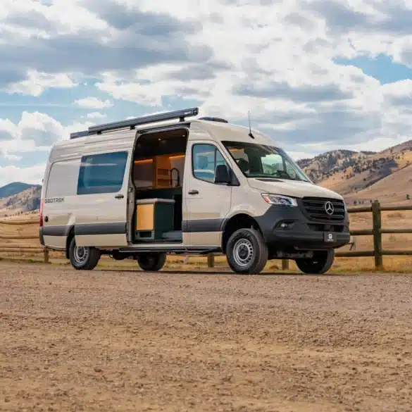 Weißer Geotrek Teton Campervan mit geöffneter Schiebetür vor einer Berglandschaft