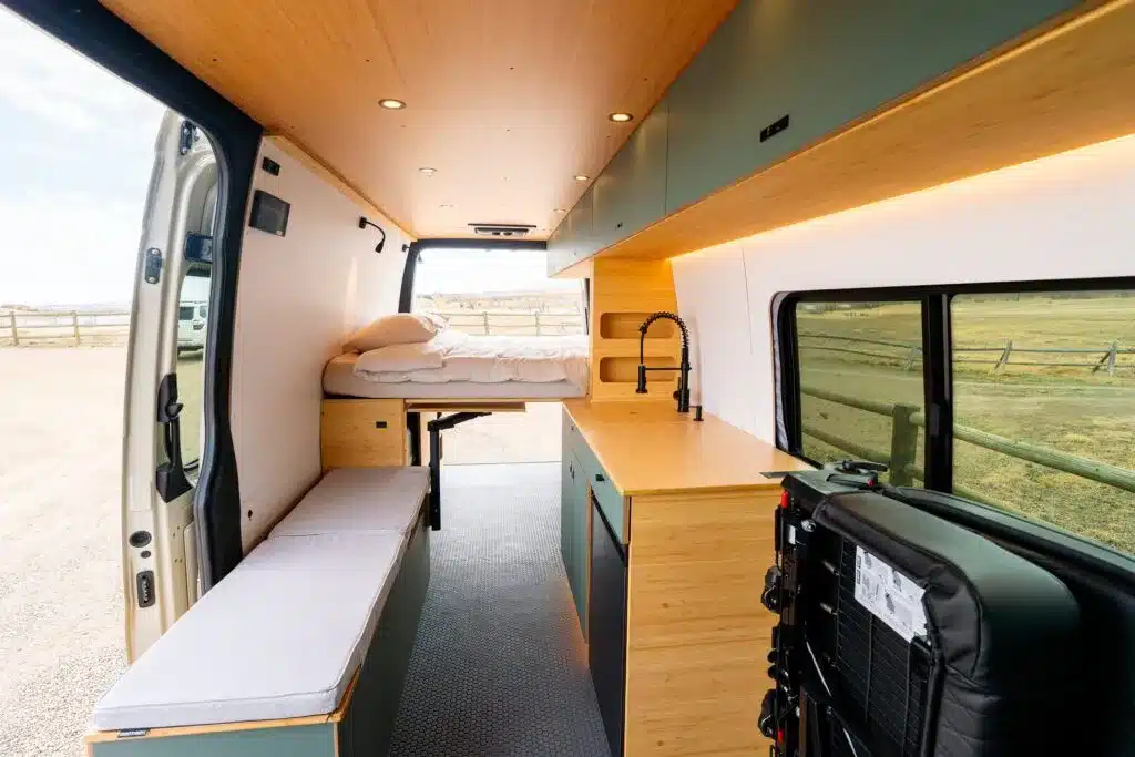 Innenraum des Geotrek Teton Campervans mit Längsbett, Küchenzeile, Spülbecken und Sitzbank