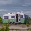 Grün-weißer Glaravan #4 Kip K550 Wohnwagen mit geöffnetem Eingang unter bewölktem Himmel