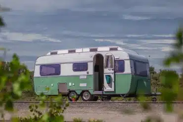Grün-weißer Glaravan #4 Kip K550 Wohnwagen mit geöffnetem Eingang unter bewölktem Himmel
