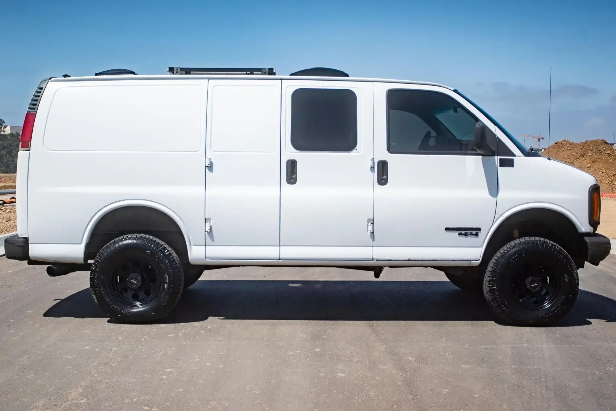 Weißer GMC Savana G2500 4x4 mit großen Geländereifen und Dachausstattung in Seitenansicht