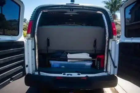 Geöffneter Laderaum eines weißen GMC Savana G2500 4x4 mit Stauboxen und Ausrüstung