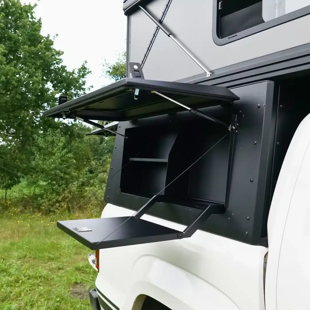 Schwarzes Aluminium-Hardtop eines weißen Pickups mit geöffneter Heckklappe und seitlichen Stauraumfächern