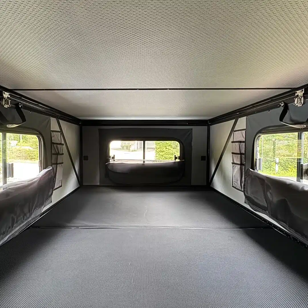 Innenansicht der Schlafkabine des OLC Adventure Hardtop PickUp Campers mit Fenstern und Stauraumfächern