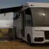 Weißes vollintegriertes HIP 4Family Reisemobil mit ausgefahrener Markise und Campingmöbeln vor einer verschneiten Landschaft