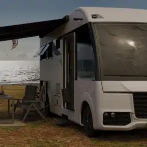 Weißes vollintegriertes HIP 4Family Reisemobil mit ausgefahrener Markise und Campingmöbeln vor einer verschneiten Landschaft