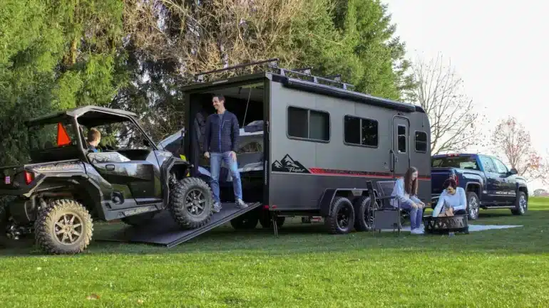 Grauer inTech Flyer Toy-Hauler mit geöffneter Heckrampe und geladenem Side-by-Side-Fahrzeug