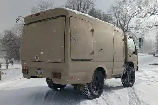 Beiger Isuzu NPR 4x4 Camper mit Fiberglasaufbau steht im Schnee