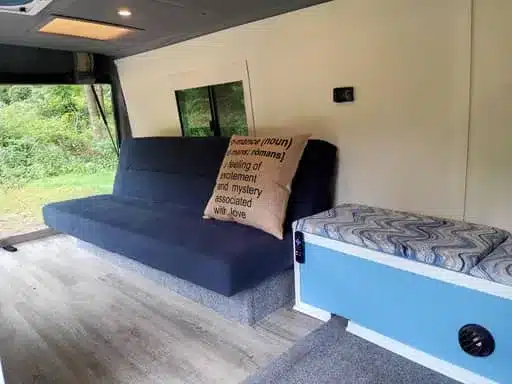 Innenraum des Isuzu NPR 4x4 Campers mit blauem Sofa und Schlafbereich