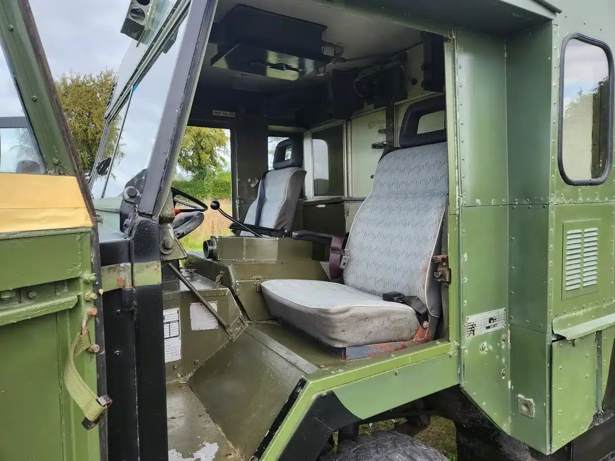 Innenraum eines grünen Land Rover 101 Forward Control Ambulance mit Fahrersitz, Beifahrersitz und militärischer Ausstattung