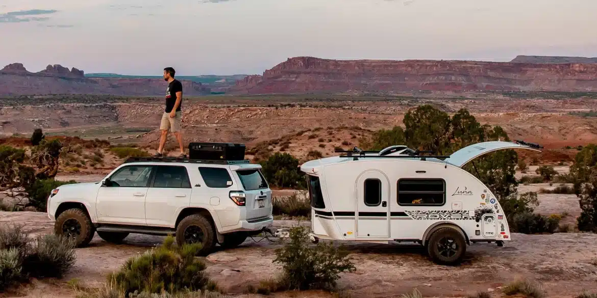 Weißer inTech Luna Teardrop-Camper neben einem SUV in einer roten Wüstenlandschaft
