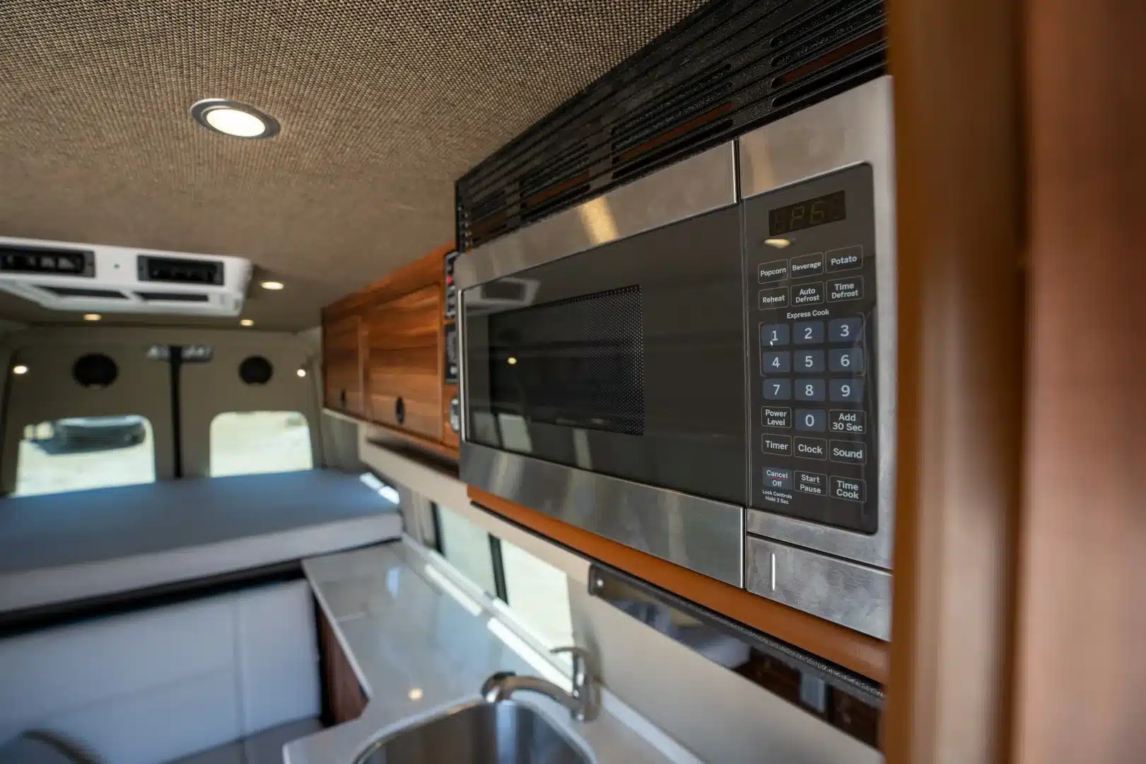 Innenraum des Millerton Campervans mit Mikrowelle, Spüle, Küchenzeile und Schlafbereich