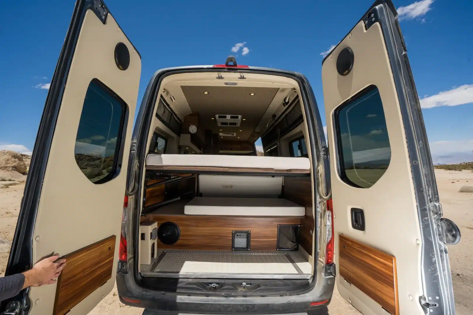 Heckansicht des ausgebauten Millerton Campervans mit geöffneten Türen, Schlafbereich und Stauraum
