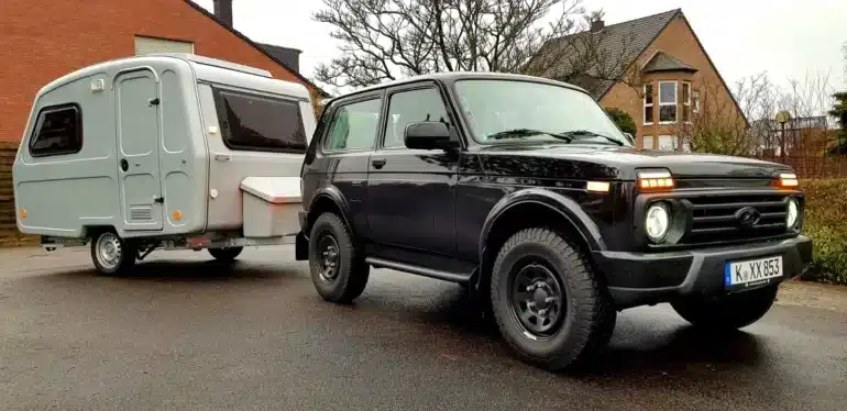 Kompakter Niewiadow N-126 D Wohnwagen mit Aufstelldach hinter einem schwarzen Geländewagen