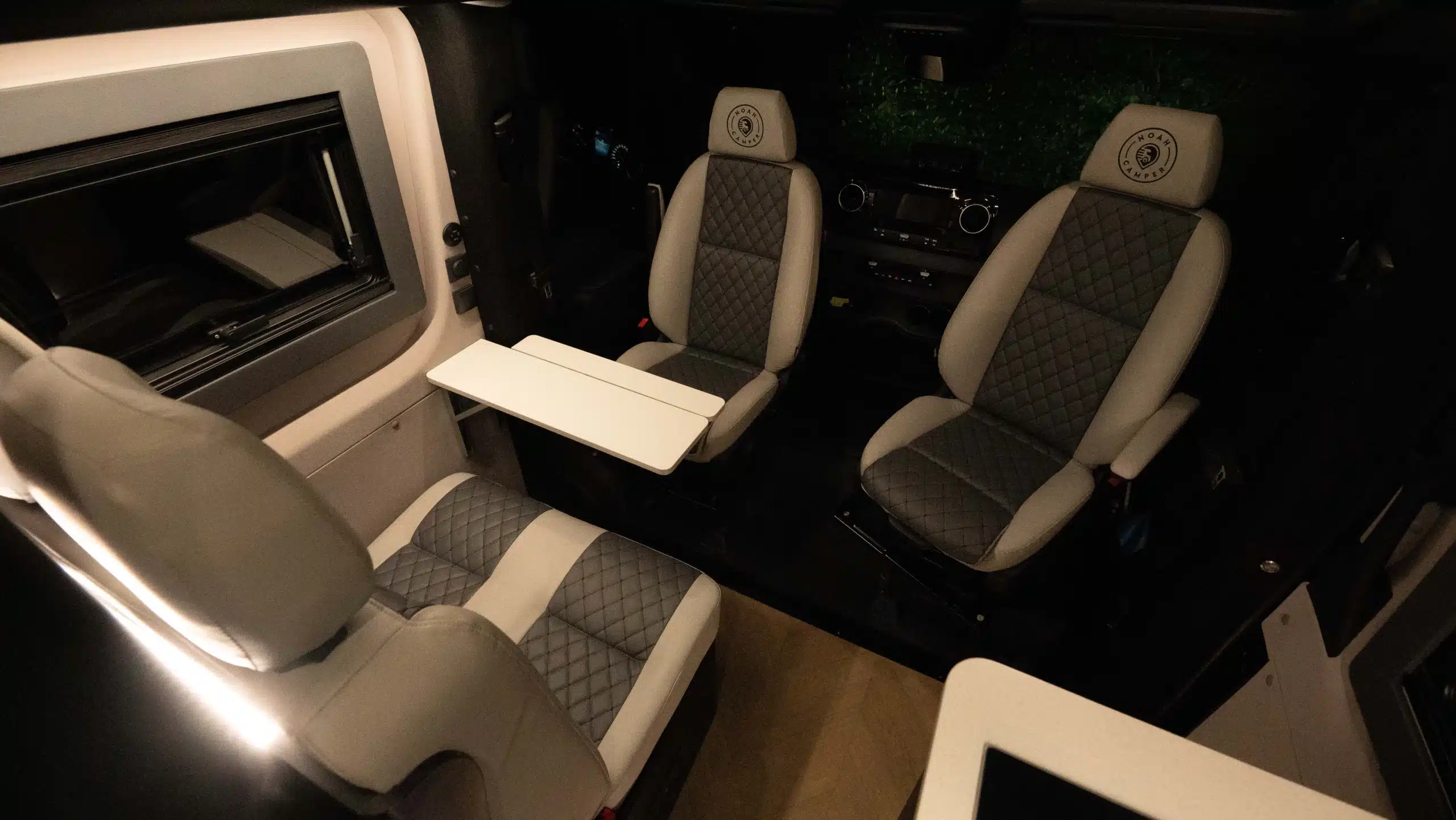 Innenraum eines Campervans mit Fahrerhaus, Sitzbereich und Tisch