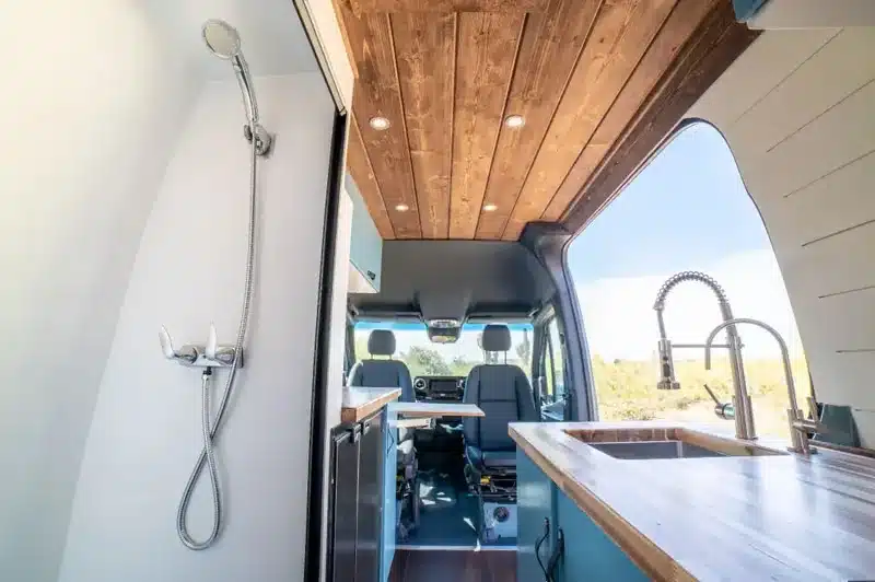 Innenraum des Olympus Off-Grid Van mit Holzdecke, Küche, Spüle und Dusche