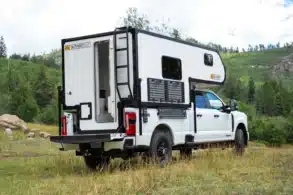 Outpost 8.0 Wohnkabine auf einem weißen Pickup in einer bewaldeten Landschaft