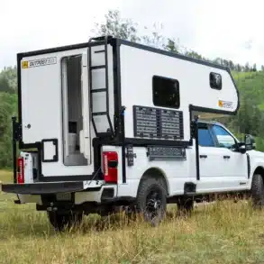 Outpost 8.0 Wohnkabine auf einem weißen Pickup in einer bewaldeten Landschaft