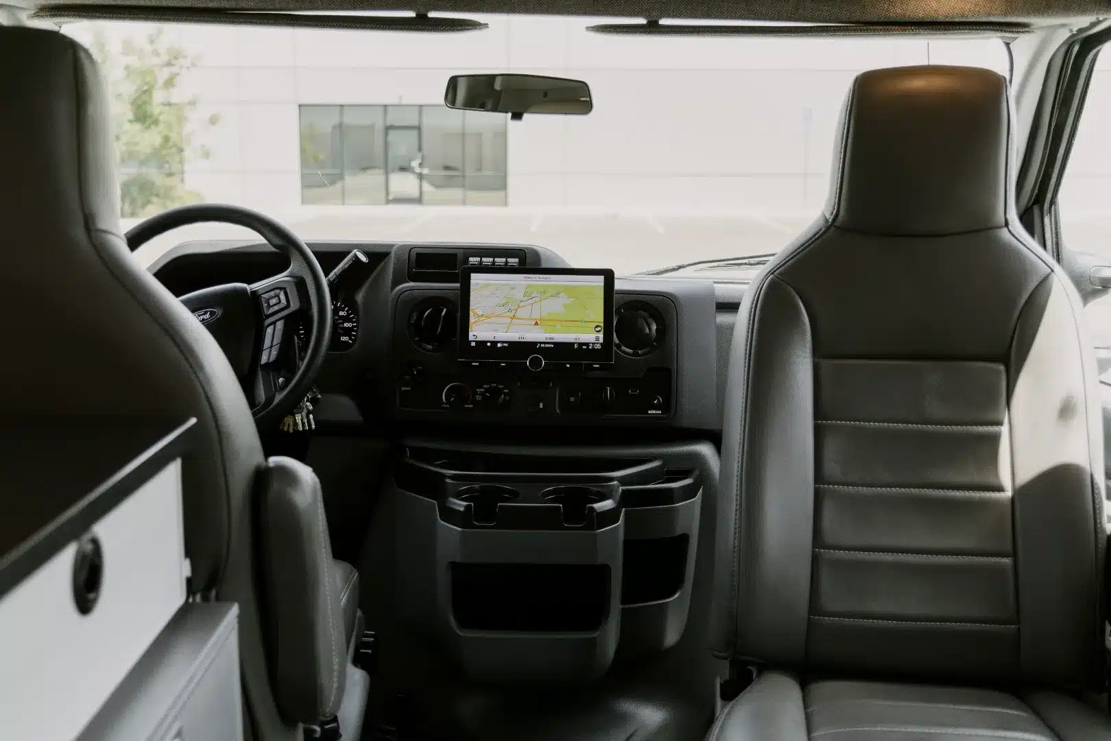 Fahrerhaus eines Ford E-350 mit Lenkrad, Armaturenbrett, Navigationssystem und Beifahrersitz