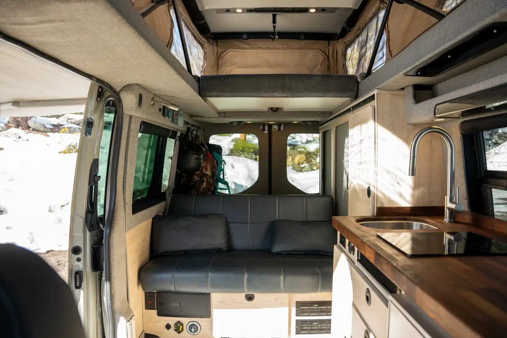 Innenraum eines Powers Sprinter Campervans mit Aufstelldach, Sitzbank, Schlafebene und Küche