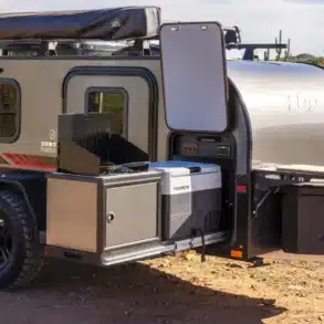 Flyer Pursue Offroad-Campinganhänger mit geöffneter Außenküche, Kühlschrank und Stauraum in einer trockenen Landschaft