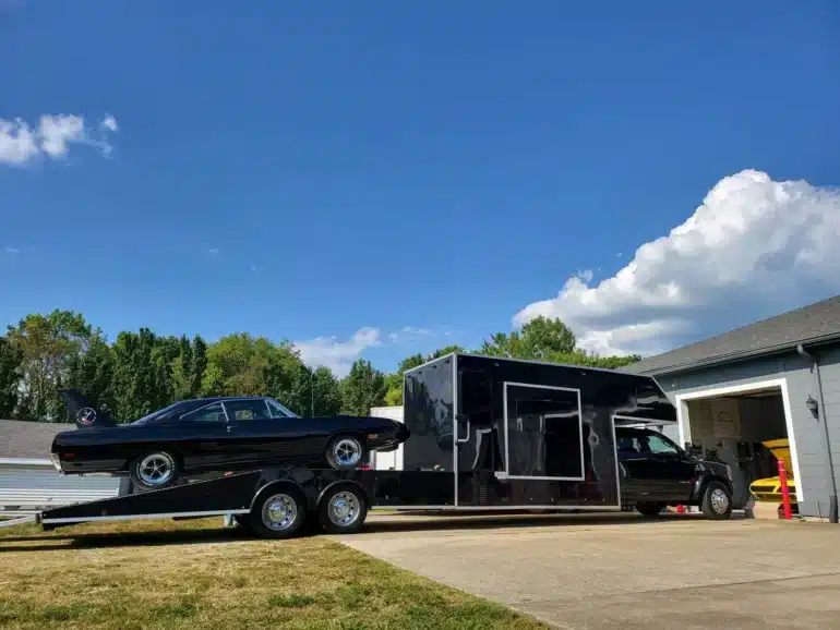 Schwarzer Ram 5500 Laramie Custom Car Hauler mit Wohnaufbau und schwarzem Fahrzeug auf der Laderampe