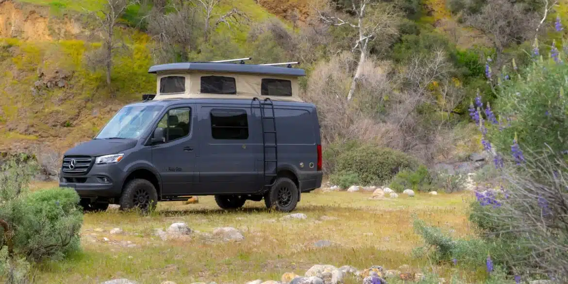 Grauer Sierra Field Van auf Mercedes-Benz-Sprinter-Basis mit geöffnetem Aufstelldach in einer felsigen Landschaft