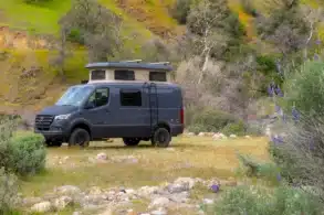 Grauer Sierra Field Van auf Mercedes-Benz-Sprinter-Basis mit geöffnetem Aufstelldach in einer felsigen Landschaft