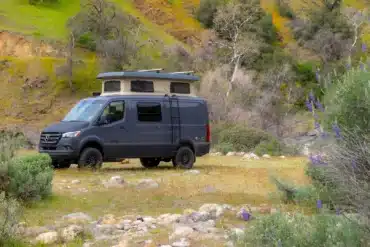 Grauer Sierra Field Van auf Mercedes-Benz-Sprinter-Basis mit geöffnetem Aufstelldach in einer felsigen Landschaft