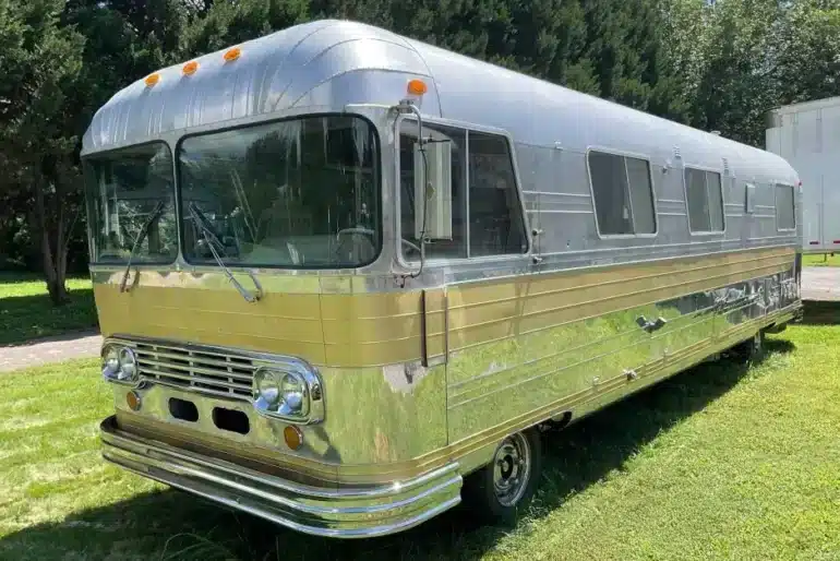 Front-Seitenansicht eines 1966 Streamline Travel Home mit silberner Aluminiumkarosserie und goldfarbenen Zierleisten auf einer Wiese