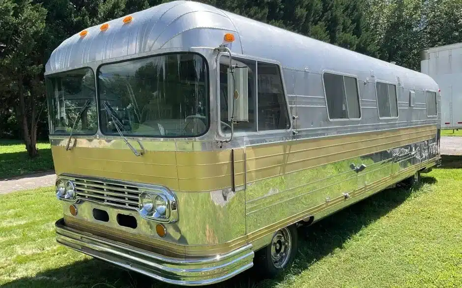 Front-Seitenansicht eines 1966 Streamline Travel Home mit silberner Aluminiumkarosserie und goldfarbenen Zierleisten auf einer Wiese