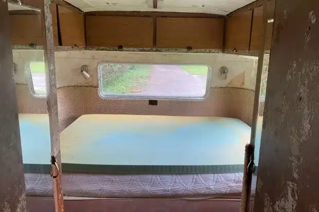 Schlafbereich mit grünem Bett und Holzschränken im 1966 Streamline Travel Home