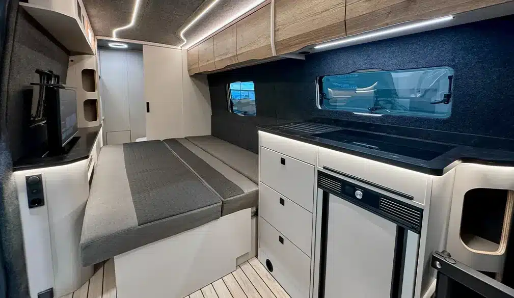 Innenraum des Rhön Camp The Seeker mit ausgezogenem Loungesofa, Küchenzeile und Oberschränken