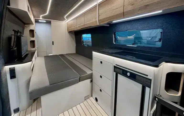 Innenraum des Rhön Camp The Seeker mit ausgezogenem Loungesofa, Küchenzeile und Oberschränken